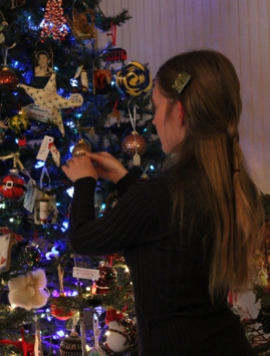 Katie decorating the tree with handmade ornaments for sale.